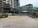 ザ東京タワーズシータワー モダンな建物の前に広がる木調デッキと開放的なガラス張りのエン