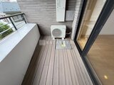 JMFレジデンス世田谷三宿 バルコニーに設置されたエアコン室外機と木調デッキ