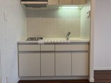 JMFレジデンス世田谷三宿 白いタイル壁と落ち着いた色合いのシステムキッチン