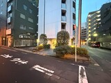 フリージアテラス 夕暮れ時に照らされた建物エントランスと緑の植栽