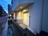 フリージアテラス 夜間に照らされたモダンなエントランスと前面道路の様子