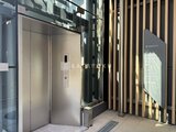グランドシティタワー月島 モダンなエレベーターホール、木調ルーバー装飾が特徴