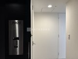 グランドシティタワー月島 戸番号が表示された玄関ドアから室内へ続く明るい廊下の様子