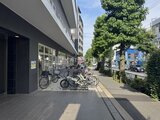 パークフラッツ学芸大学 建物前の歩道に自転車が停まる明るい街並みの様子