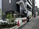 ザ・パークハビオ北千住 モダンな外観のエントランスと緑を配した前面道路の様子