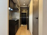 ブランシエスタ目黒中央町 黒を基調としたモダンなキッチンから玄関方向を見た廊下の様子