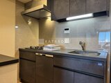 ブランシエスタ目黒中央町 モダンな黒基調のキッチン、コンロとシンク付きの調理スペース