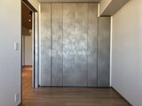 ブランシエスタ目黒中央町 落ち着いた色合いの洋室とグレー調のクローゼット扉がある空間