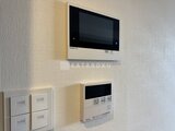 RJRプレシア蒲田 壁付きのインターホンと給湯器パネルが並ぶ玄関周り