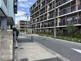 ロイジェント西新井 敷地内通路から見た大型マンション棟と周辺街並みの様子