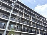 ロイジェント西新井 明るい空を背景にした、規則的なバルコニーが並ぶ建物外観