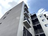 ロイジェント西新井 白とグレーのモダンな外観に複数のバルコニーが配置された建物
