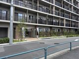 ロイジェント西新井 緑を配した1階エントランスと整然とした外観の集合住宅