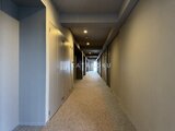 ロイジェント西新井 落ち着いた照明が灯る共用廊下と複数の住戸入口