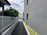 ロイジェント西新井 白いフェンスと緑に囲まれた落ち着いた印象の共用通路