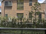 ロイジェント西新井 緑の植栽を配した落ち着いた印象のレンガ造り建物外観