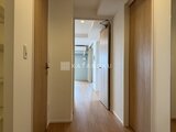 ロイジェント西新井 木目調のドアが並ぶ明るい廊下の奥行きある様子