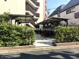 クレアティフ三軒茶屋 生垣に囲まれた駐輪場とカーポートのある共用部分
