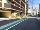 クレアティフ三軒茶屋 駐車場入口と植栽が配置されたモダンな建物外観