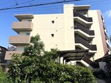 クレアティフ三軒茶屋 青空を背景にした、モダンなデザインの白とベージュ色の建物外観