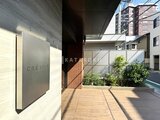 クレアティフ三軒茶屋 建物名表記のあるエントランス周辺から見た、緑を配置した開放的