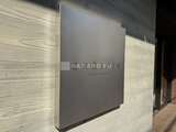 クレアティフ三軒茶屋 木目調の壁面に取り付けたグレーの物件名サイン