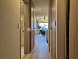 クレアティフ三軒茶屋 木目調のドアが並ぶ廊下から明るいリビングへ続く開放的な空間
