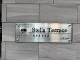 ステラテラス グレーのタイルが配された建物のエントランスに掲げられた物件の