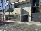 コージーコート谷中 前面道路から見たコンクリート造の建物エントランスと駐輪場
