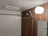 リビオメゾン浅草雷門 木目調の壁面とシャワーヘッド、丸窓が備わったバスルーム