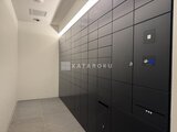 プラウドフラット西蒲田 黒を基調とした宅配ボックスが設置された明るい共用部廊下