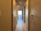 プラウドフラット西蒲田 複数の扉が並ぶ廊下から見たバルコニーへの開放的な通路