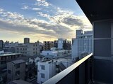 プラウドフラット西蒲田 バルコニーから見た開放的な都市風景と夕焼け空