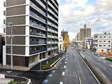 アリビス五反野 前面道路から見たモダンな建物外観と周辺街並み