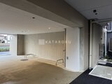 アリビス五反野 建物の明るいエントランスホールから街路側を見た通路の様子