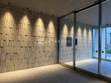 アリビス五反野 明るい照明が映り込む大きなガラス扉と幾何学模様の壁面が特徴的