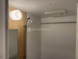 アリビス五反野 木目調のアクセント壁と白い円形照明がある浴室