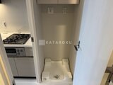 ルフォンプログレ赤羽マークス 洗濯機置き場と奥に見えるキッチンの動線を備えた居住空間