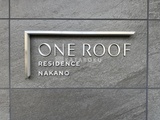 ワンルーフレジデンス中野 グレーの石張り壁面に施された建物の銘板プレート