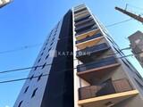 シーズンフラッツ大森西 青空を背景にした建物の縦長の外観、バルコニーと窓が規則正しく