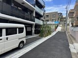 コンフォリア・リヴ大崎 駐車スペース付きの現代的なマンション外観と前面道路の様子