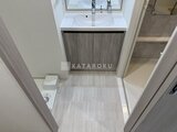コンフォリア・リヴ大崎 落ち着いた色合いの洗面化粧台と トイレが配置された洗面脱衣室