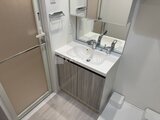 コンフォリア・リヴ大崎 白を基調とした清潔感のある洗面化粧台と浴室入口