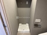 グランジット月島TOKYO BAY トイレ空間を上から見た様子で、白い便器と落ち着いた色合いの壁