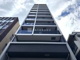 ジーグランデ西日暮里 下から見上げた整形のマンション外観と青空