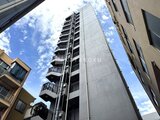 ジーグランデ西日暮里 下からあおった視点で見た建物外観、青空に映える縦長のモダンな