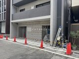 ジーグランデ西日暮里 建築中の建物正面、工事用コーンが並ぶエントランス周辺の様子