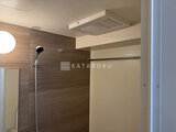 ドゥーエ三ノ輪3 天井に浴室乾燥機を備えた、ブラウン調タイルの広々としたバスル