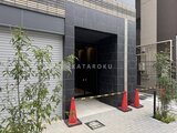 ACPレジデンス中野新橋 黒いタイル貼りのモダンな建物エントランス、植栽に囲まれた入口