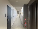 ACPレジデンス中野新橋 廊下奥へ続く共用通路、モダンな扉と消火器が配置された様子